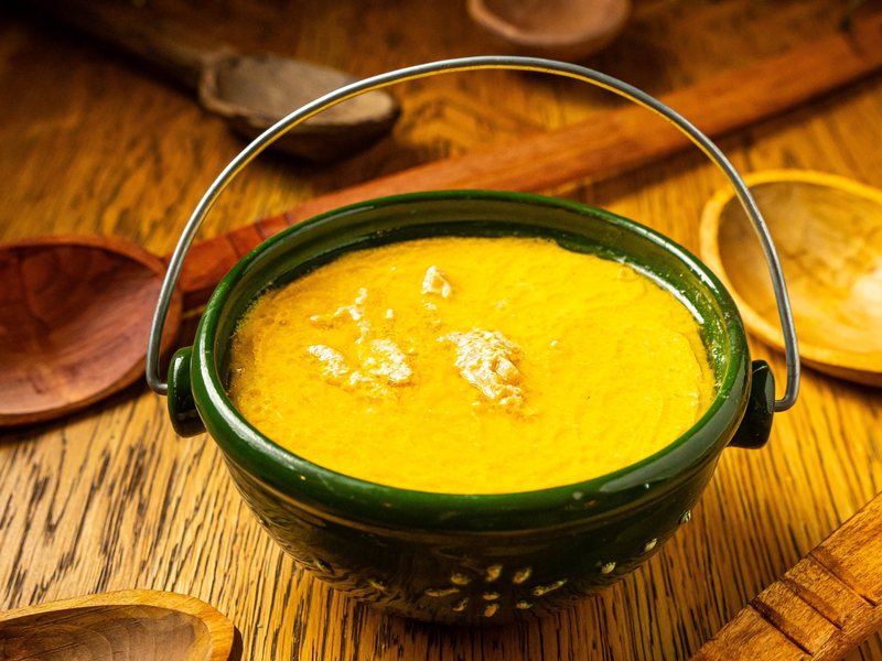 Ciorbă de burtă, Romanian tripe soup, in a green ceramic pot with a handle at Restaurant Ceaun