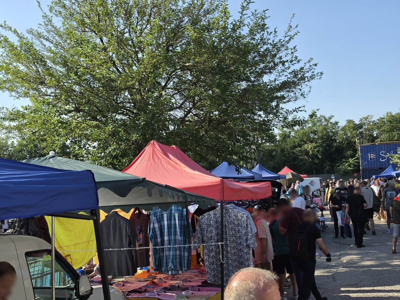 Crowds walking between canopied clothing stalls at Valea Cascadelor market in Bucharest