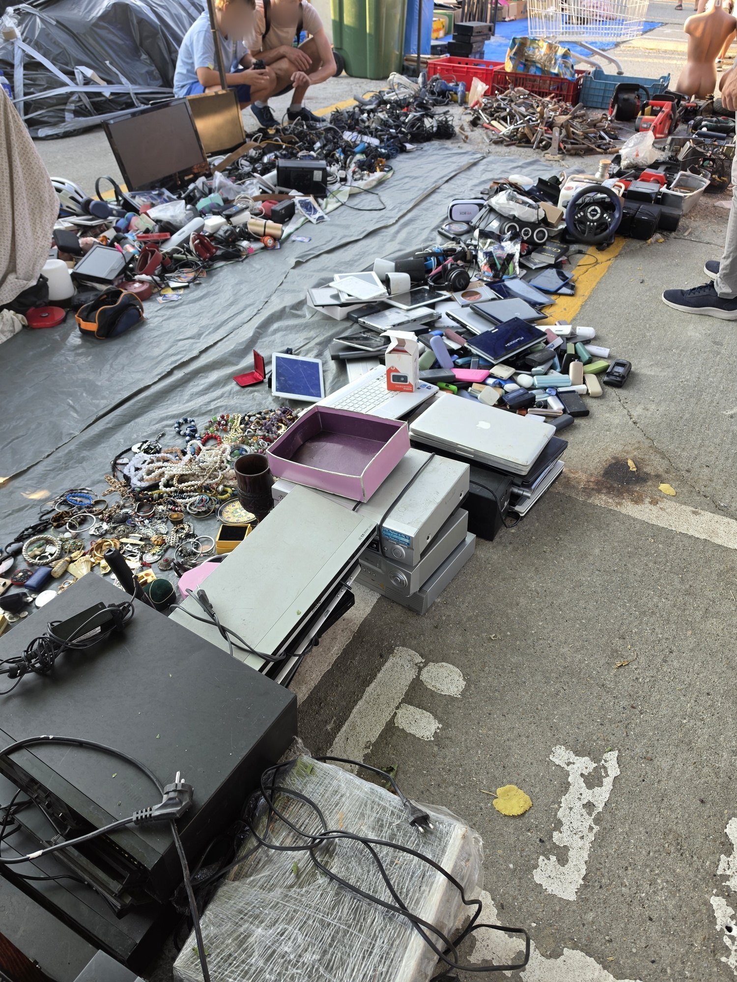 Laptops, tablets, cables and small electronics spread out on a tarpaulin at the Bucharest flea market