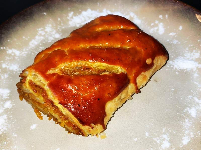 O porție de plăcintă cu dovleac, rumenită și lucioasă deasupra, pe o farfurie pudrată cu zahăr, la Restaurant Ceaun